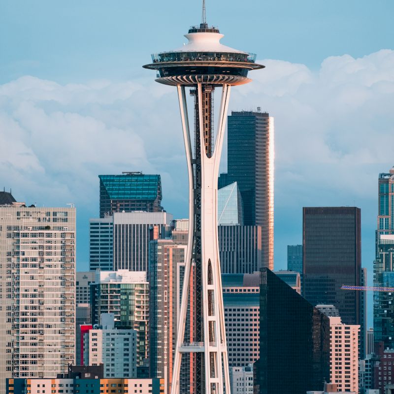 The image displays the Seattle skyline with the iconic Space Needle prominently in the center, surrounded by modern skyscrapers and buildings.
